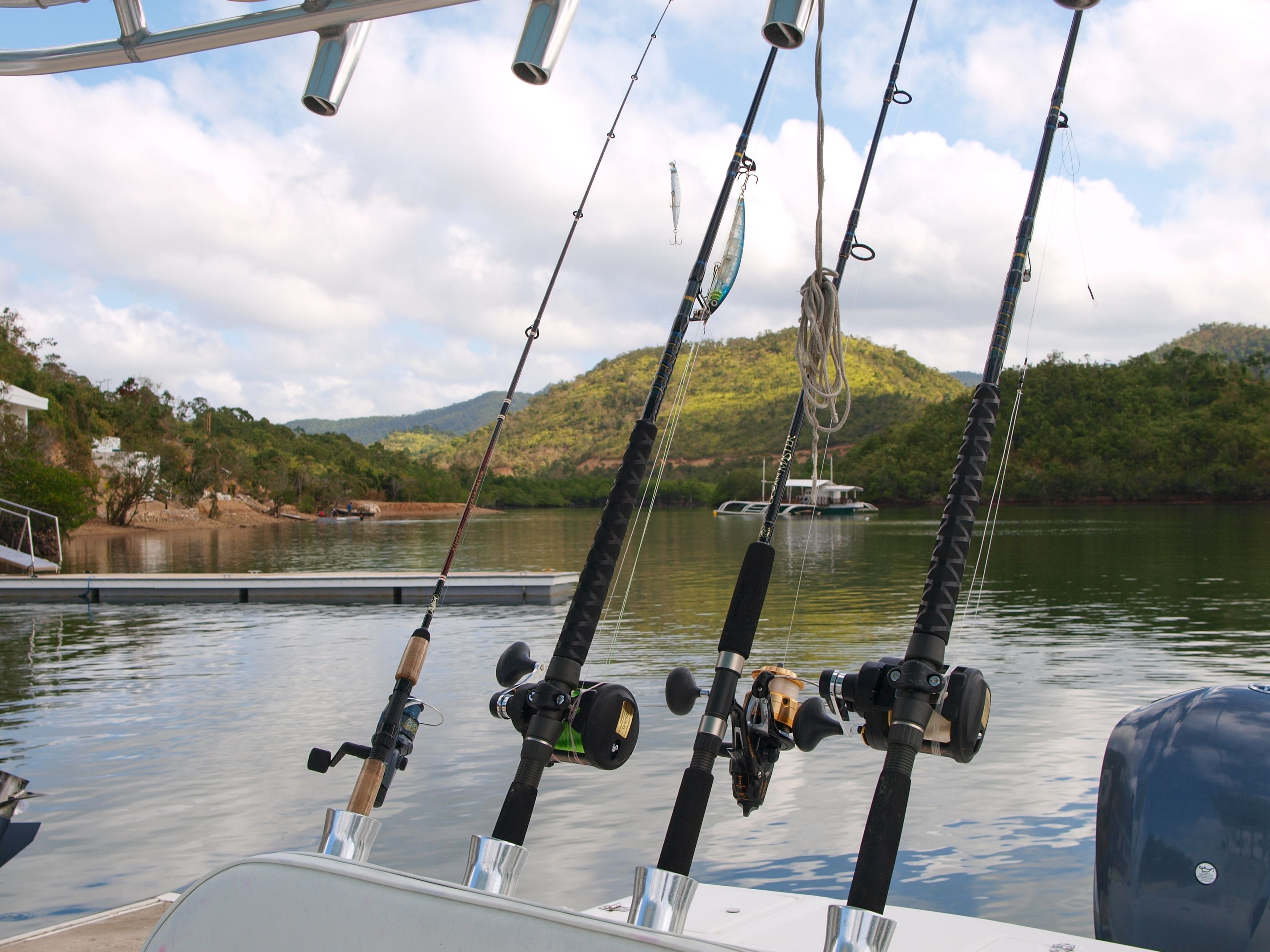 Fishing rods on a boat with a lake and hills in the background.