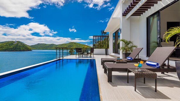 A modern infinity pool with a clear view of the sea and hills, outdoor seating with cushions, and a glass door entrance. - Busuanga Bay Lodge (Busuanga)