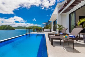 A modern infinity pool with a clear view of the sea and hills, outdoor seating with cushions, and a glass door entrance. - Busuanga Bay Lodge (Busuanga)