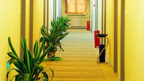 A hotel hallway with a yellow carpet, potted plants, and doors on both sides. - Shanshui Trends Hotel Liu Li Qiao (Beijing)
