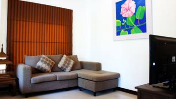 Una sala de estar con un sofá, una televisión y un cuadro en la pared.