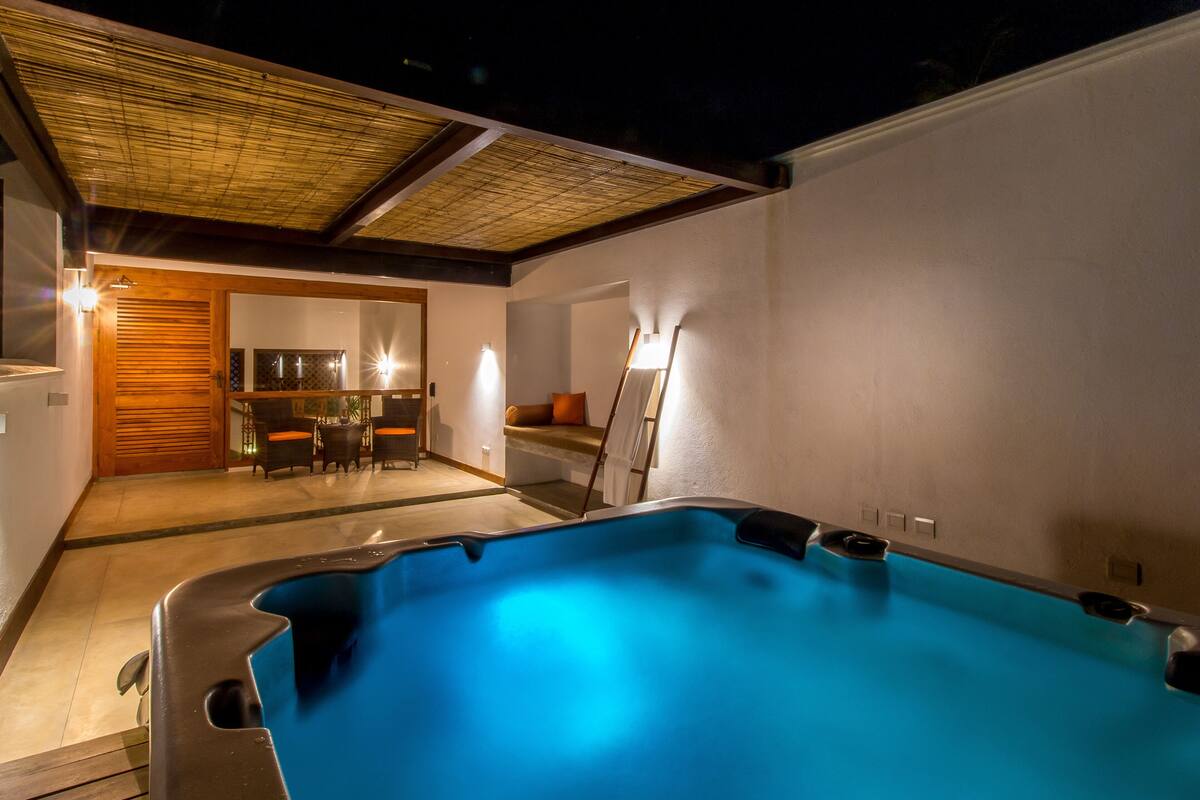 Ein Poolbereich mit Whirlpool, einer Holztür und einem Essbereich mit Stühlen und Tisch.