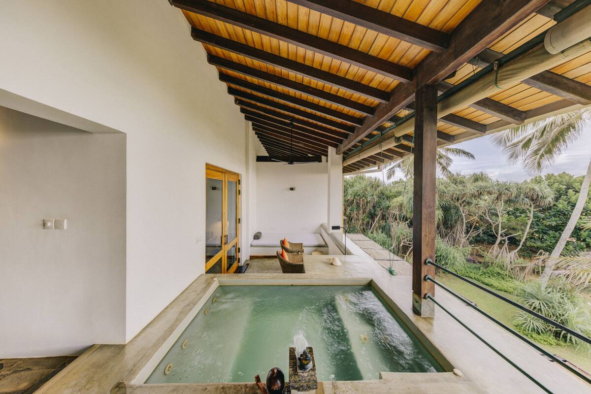 Wellnessbereich mit Pool, Holzboden und Blick auf Palmen.