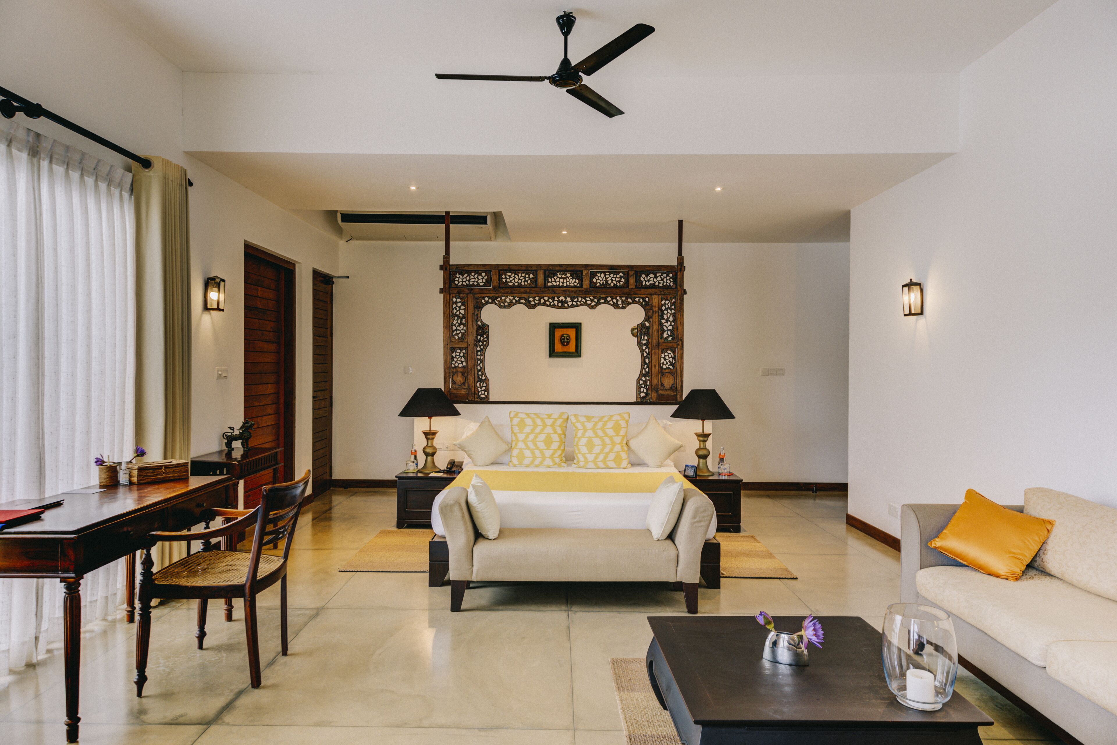 A spacious living room with a large bed, a sofa, a dining table, and a coffee table.