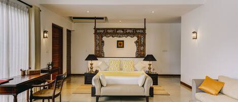 A spacious living room with a large bed, a sofa, a dining table, and a coffee table.