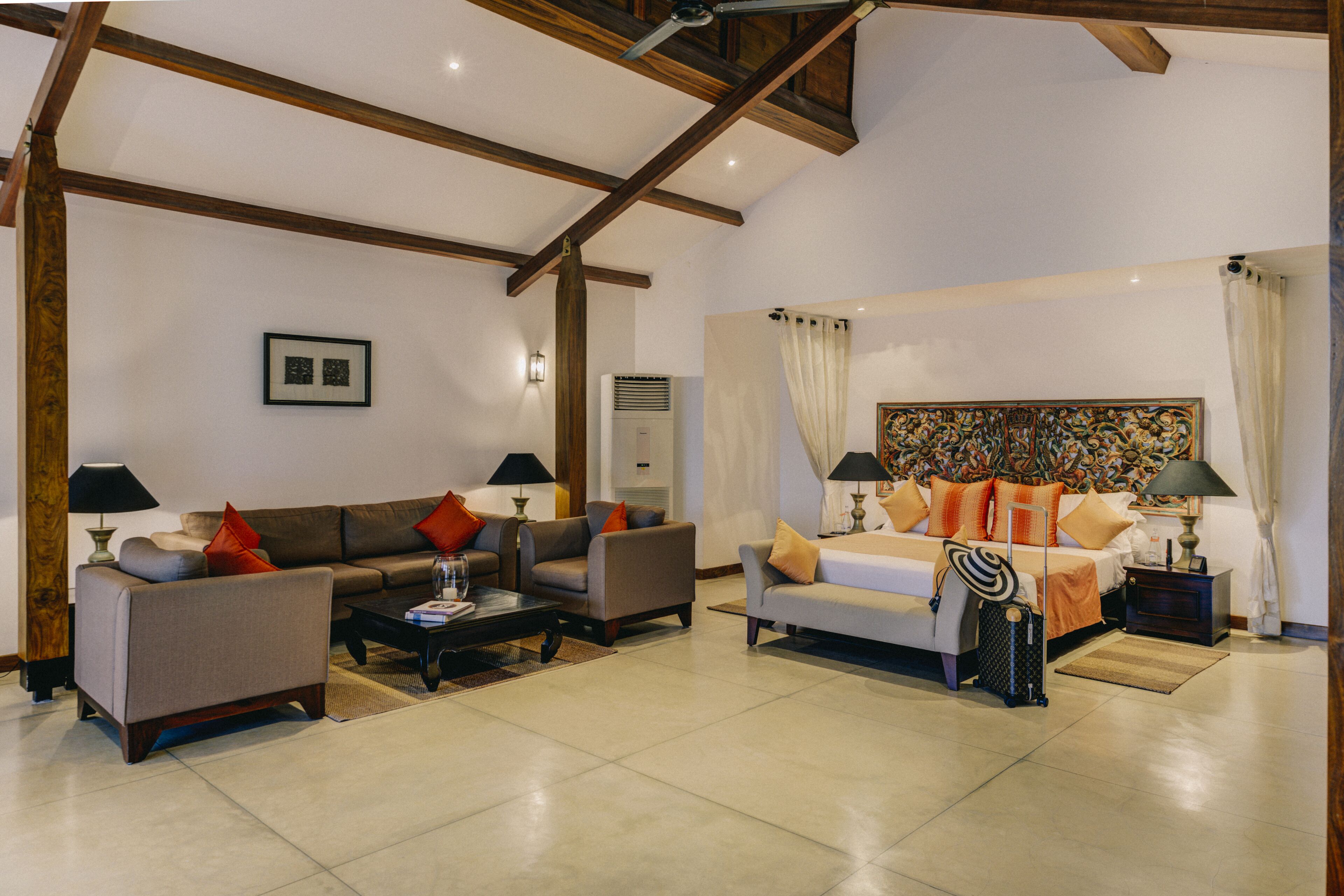 A spacious living area with a sofa set, a coffee table, and a bed with a headboard.