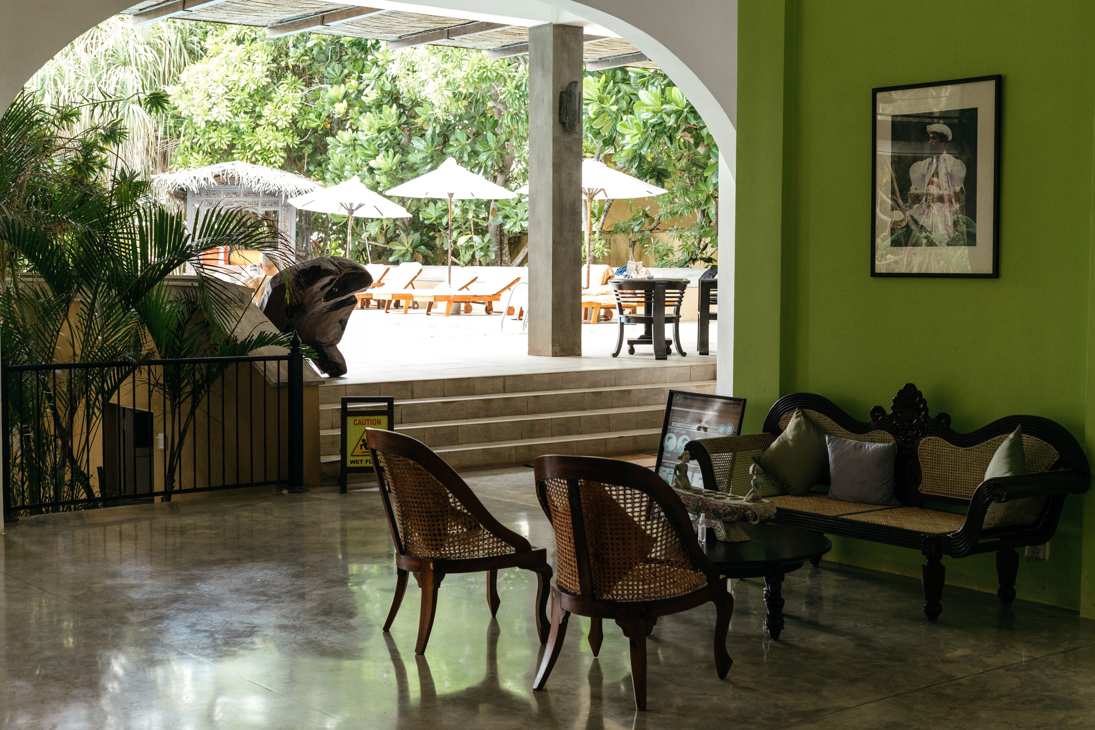 Un vestíbulo con mostrador de recepción, zona de estar y vistas del patio exterior con sombrillas.