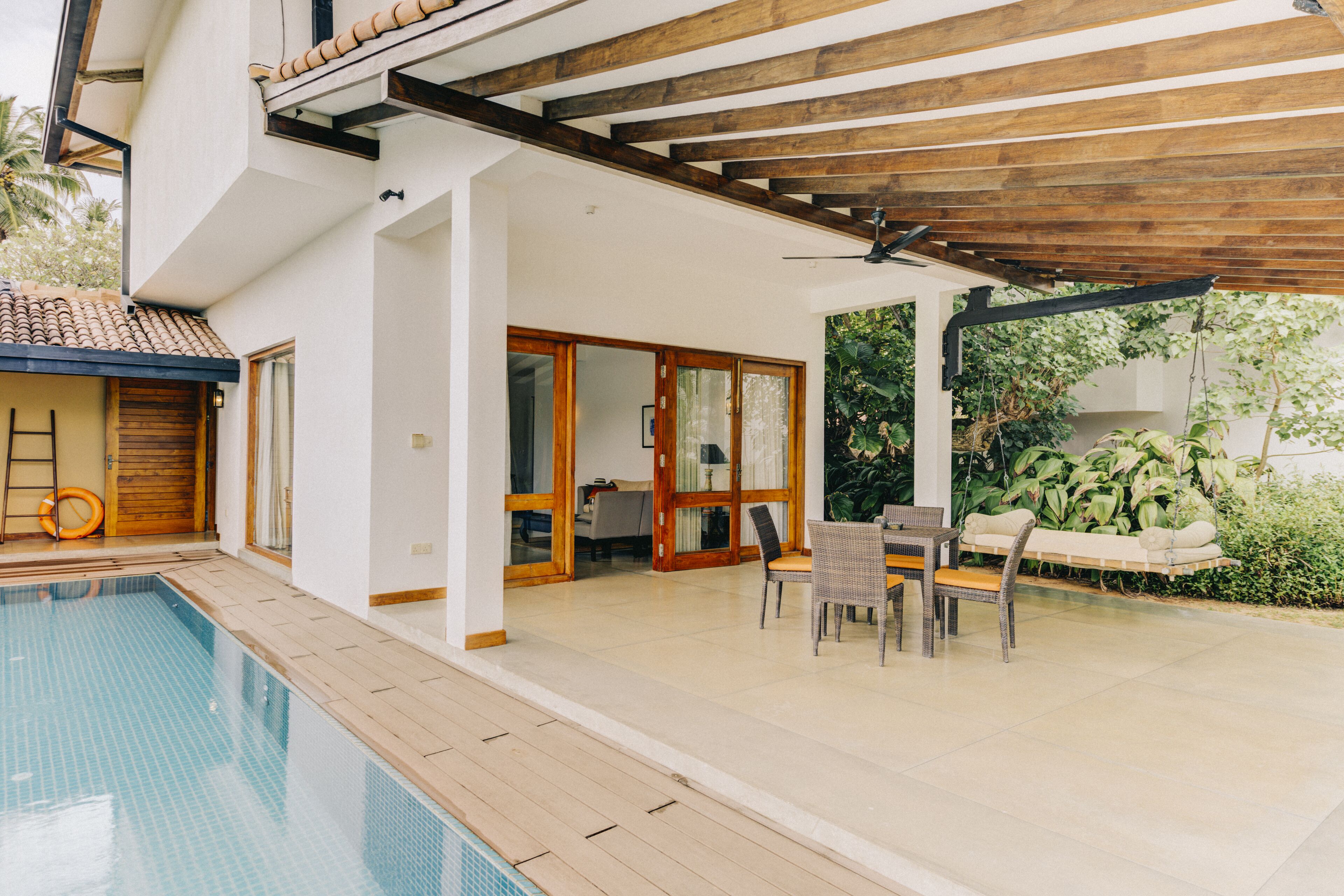 A modern house with a swimming pool, wooden deck, and a covered patio area.