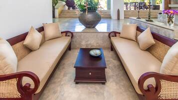 A lobby with two sofas, a coffee table, and a large vase with flowers.