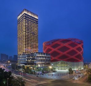 A modern hotel with a distinctive geometric facade and a large, illuminated dome structure.