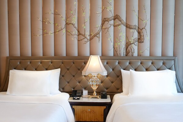 A hotel room with a tufted headboard, a bedside table with a lamp, and a decorative wall panel.