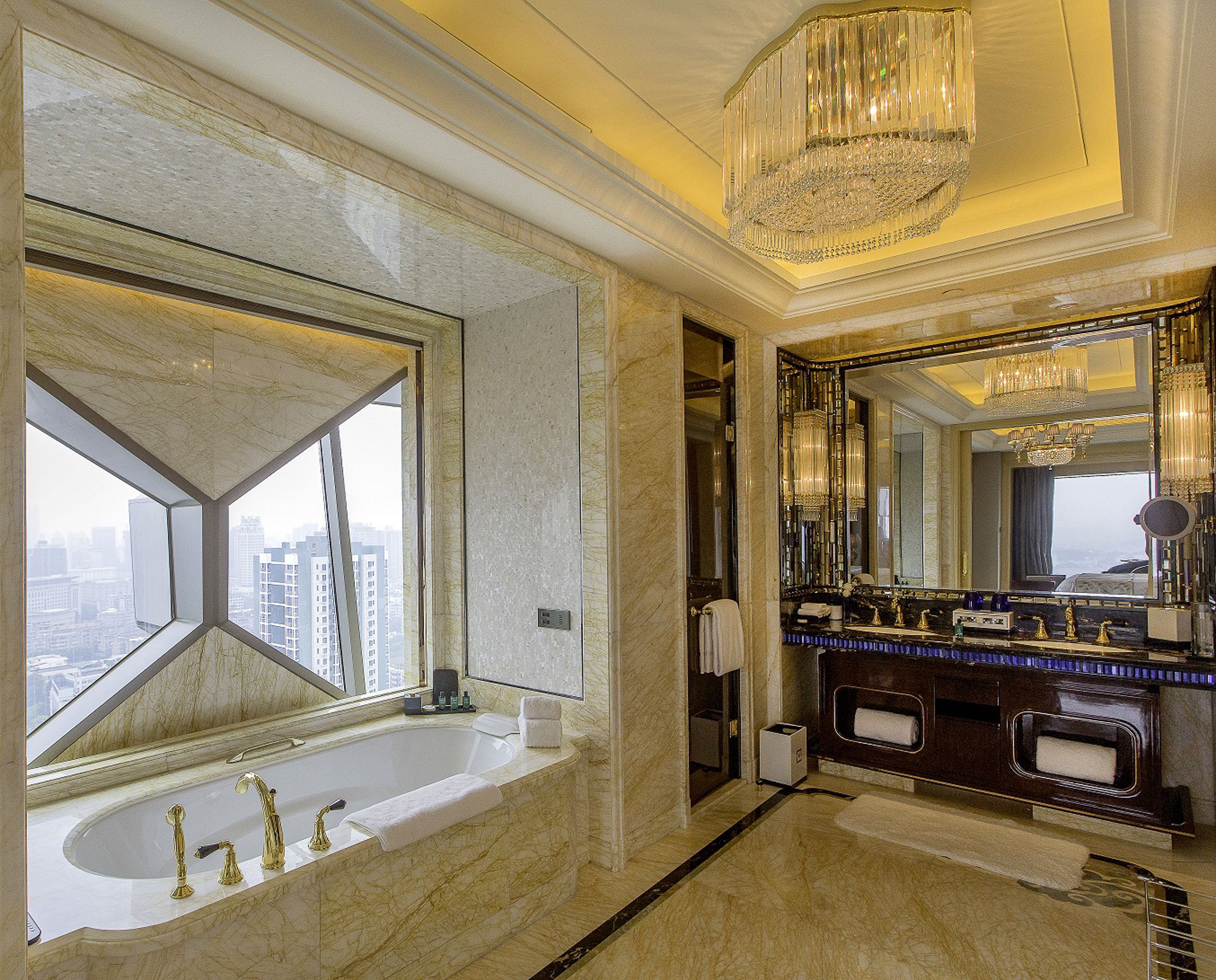 A luxurious bathroom with a large bathtub, a mirror with a decorative frame, and a chandelier.