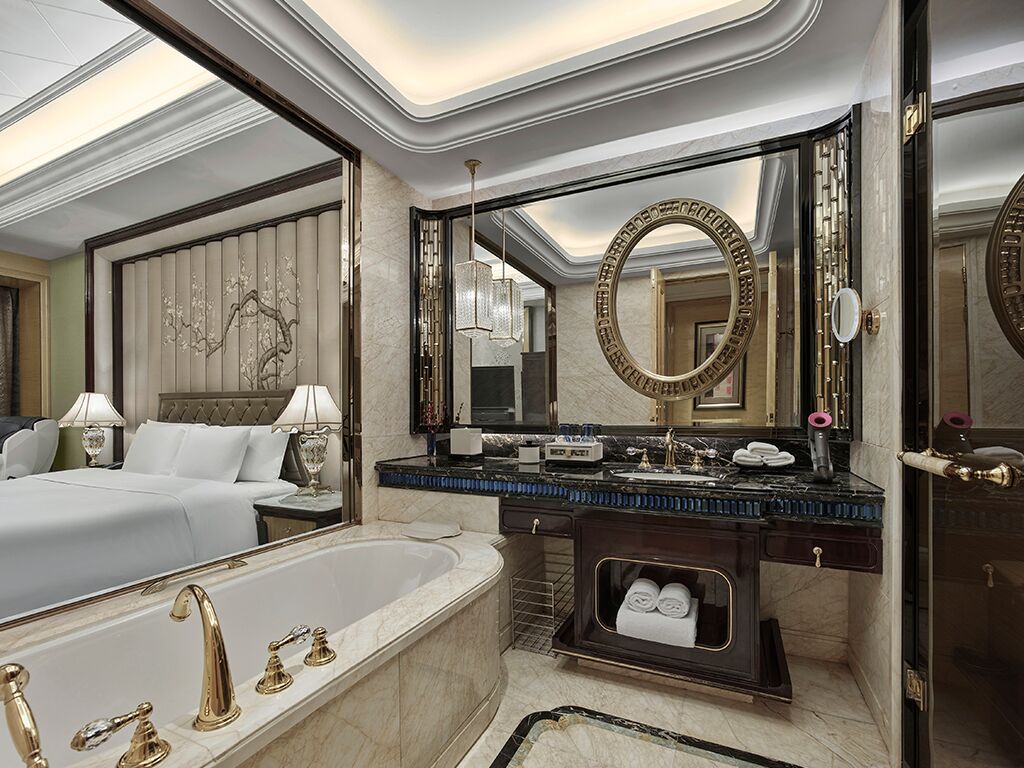 A luxurious bathroom with a large bathtub, a vanity with a mirror, and a separate bedroom area.