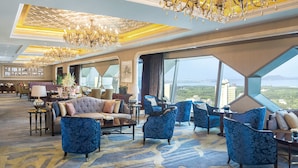 Eine großzügige Lobby mit hoher Decke, großen Kronleuchtern und einer Sitzecke mit Sofas und Sesseln.