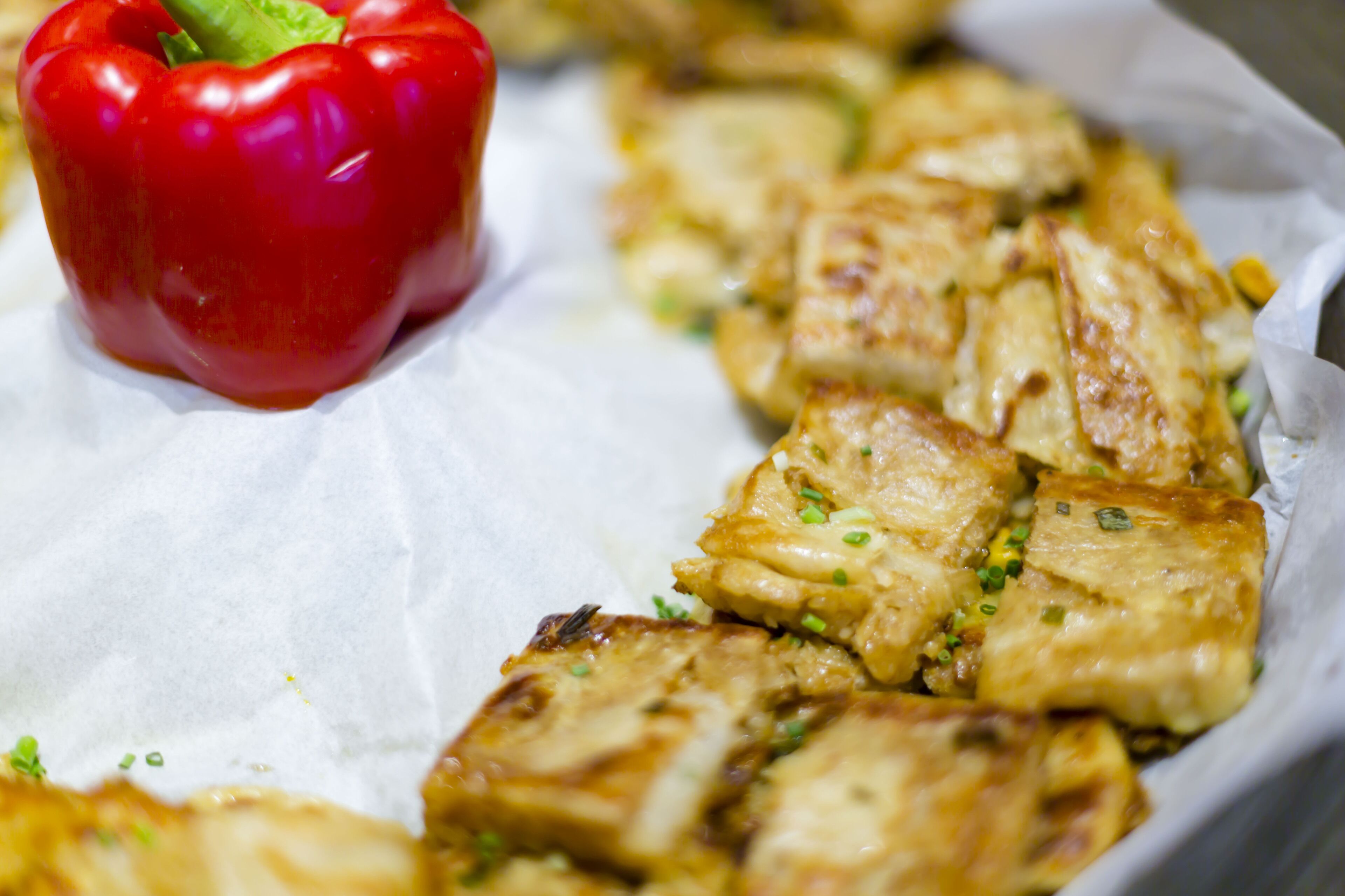 A tray of grilled chicken pieces with a red bell pepper.