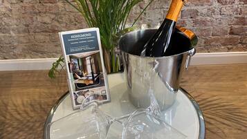 A bottle of champagne in a metal bucket with a glass on top, a brochure for Honigmond Boutique Hotel, and a plant in the background.