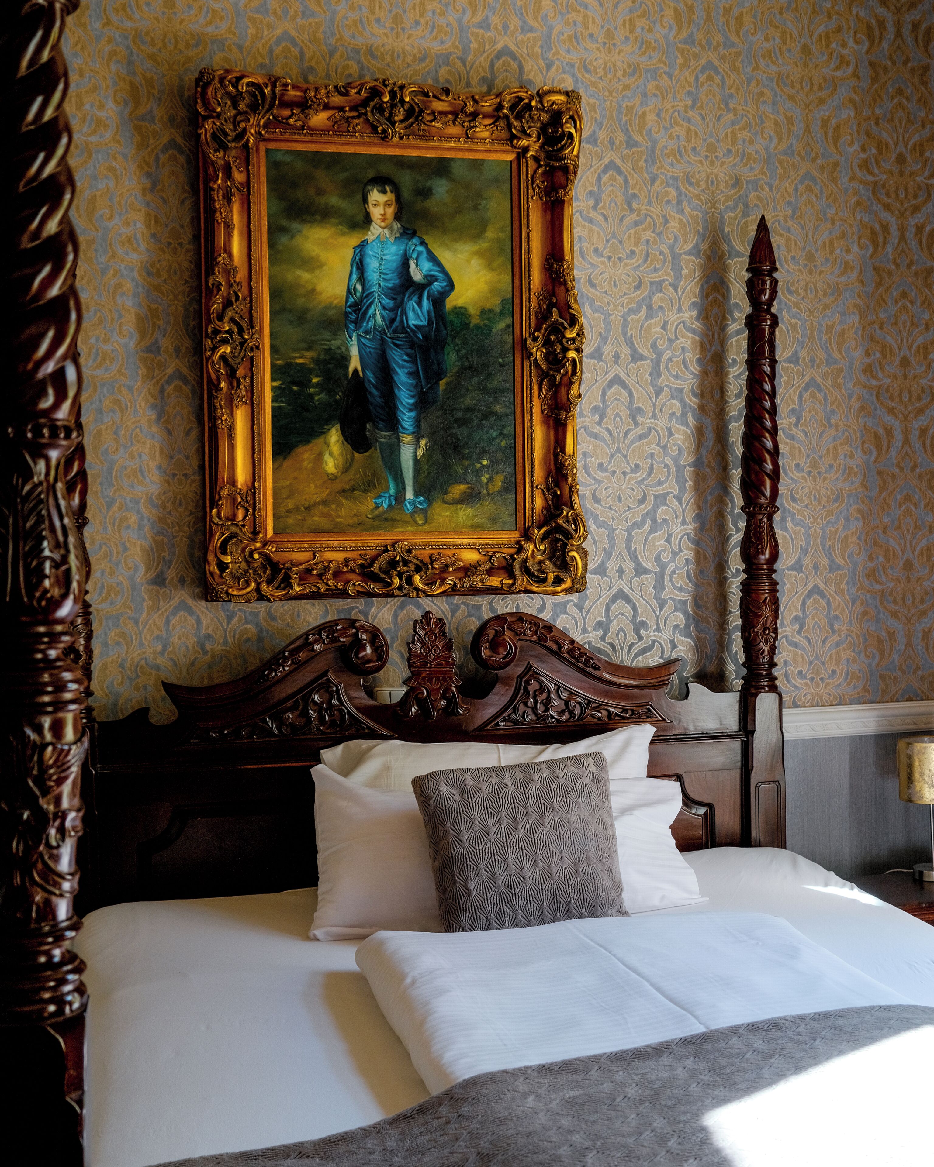 A bed with a headboard, a painting, and a lamp.