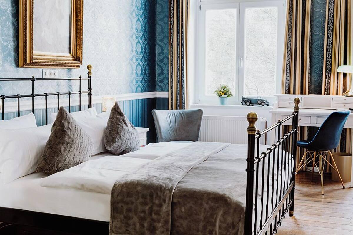 A bedroom with a bed, a desk, a chair, and a window.