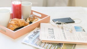 A breakfast setting with croissants, a bottle of juice, and a newspaper on a table. - Nova Domizia (Rome)