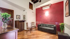 A lobby with a wooden reception desk, a black leather sofa, and a red accent wall. - Nova Domizia (Rome)
