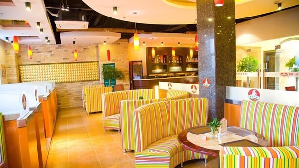 A hotel lobby with striped seating, a reception desk, and a bar area.