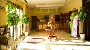 A lobby with a reception desk, a chandelier, and potted plants.
