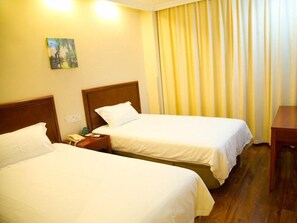 A hotel room with two single beds, wooden headboards, a bedside table with a lamp, a painting on the wall, and a window with yellow curtains. - GreenTree Inn Shanghai Pudong New Area Chuansha Road Kayuan Business Hotel (Shanghai)