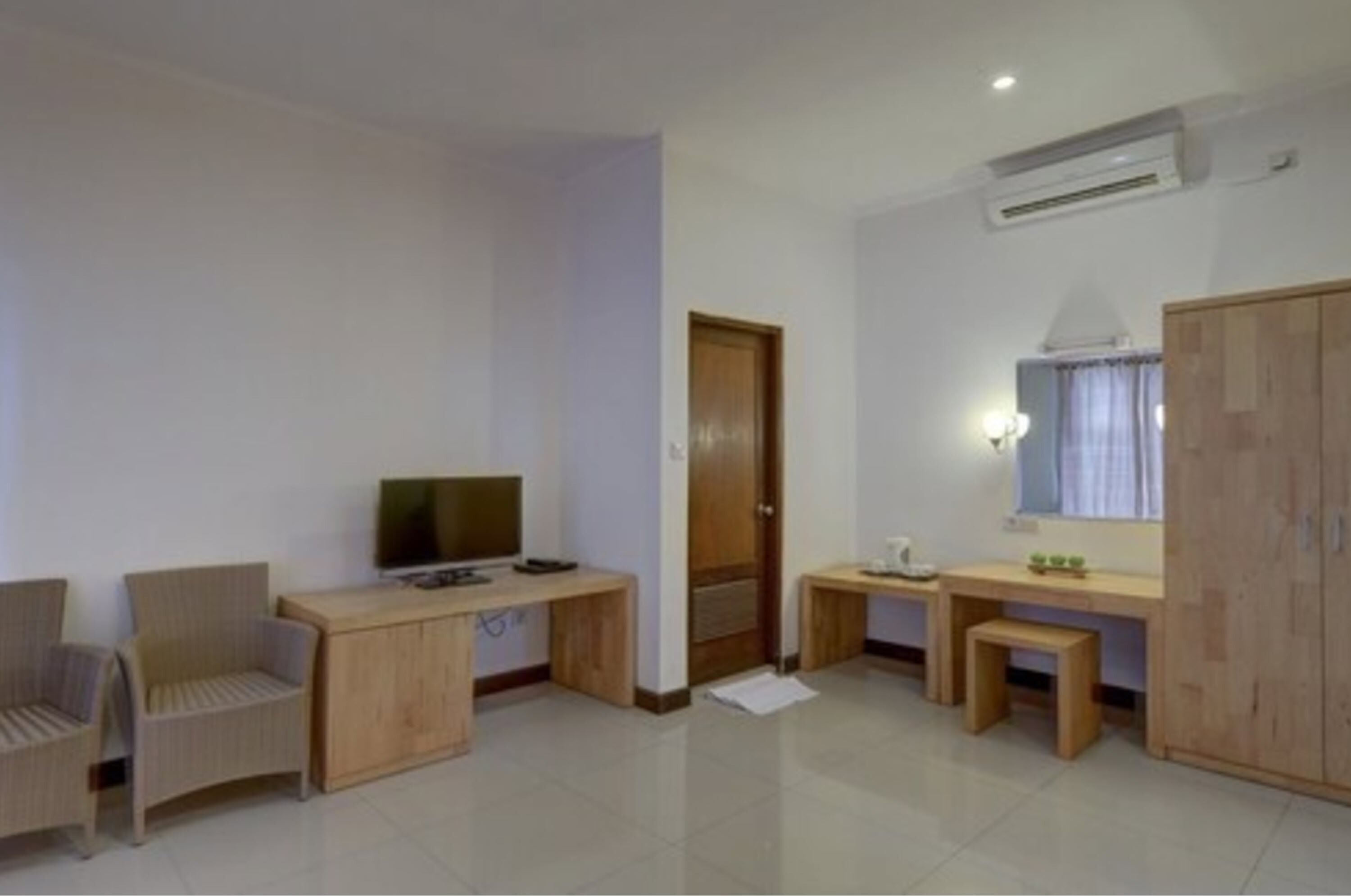 A room with a desk, two chairs, a television, a wardrobe, and a mirror.