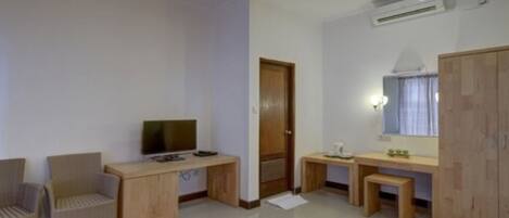 A room with a desk, two chairs, a television, a wardrobe, and a mirror.