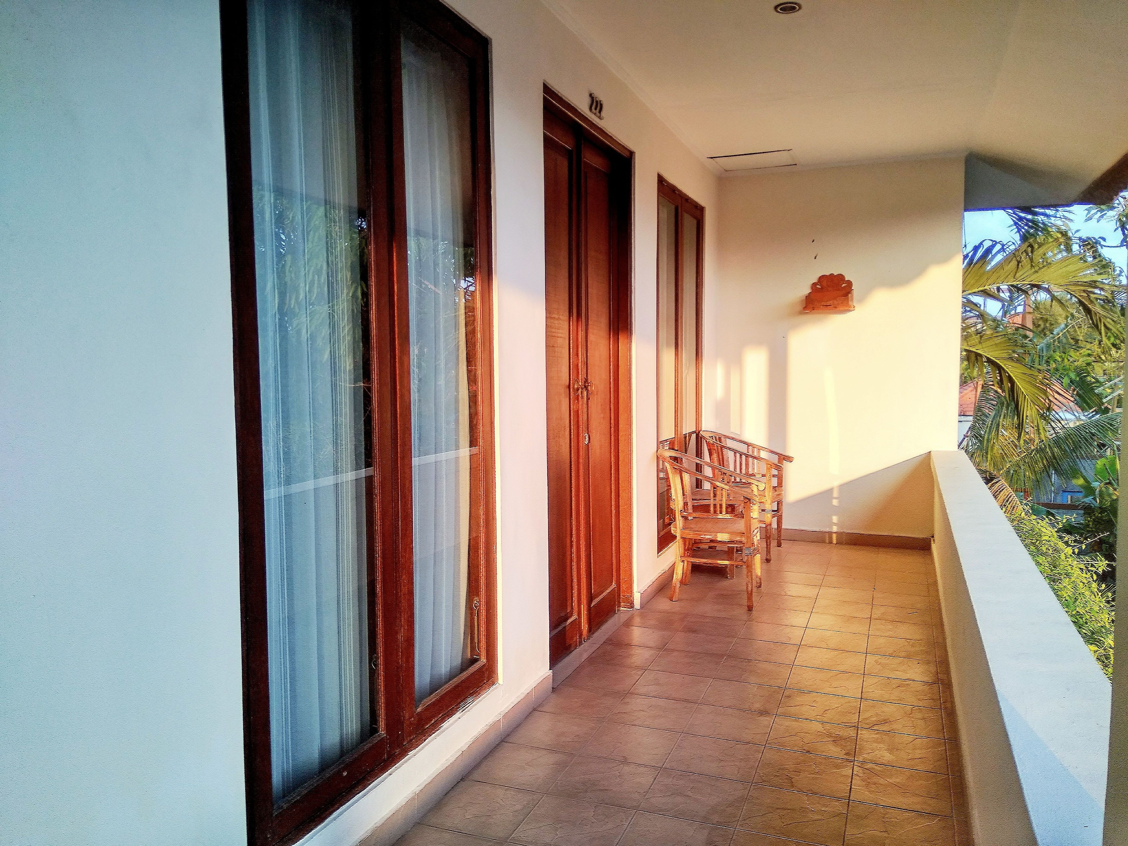 A balcony with a tiled floor, wooden doors, and a chair.