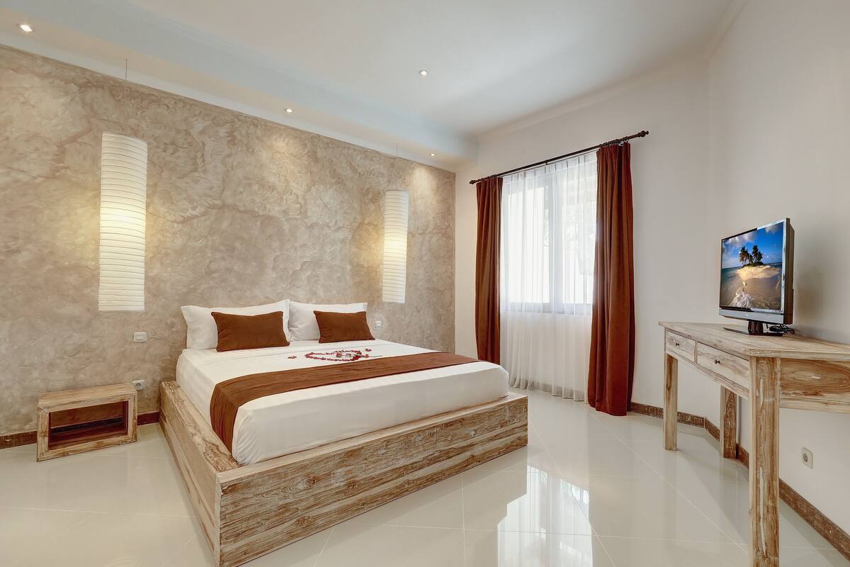 A modern bedroom with a large bed, a wooden nightstand, a TV, and a marble wall.