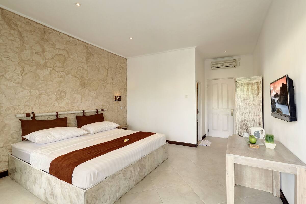 A bedroom with a bed, a desk, and a television.