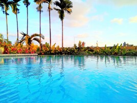Piscina rodeada por palmeiras e plantas tropicais.
