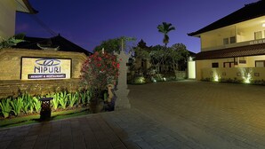 A well-lit hotel entrance with a signboard, paved driveway, and landscaped garden. - Nipuri Hotel (Keroboken Kelod)