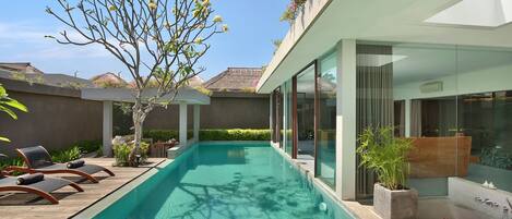 A modern pool area with lounge chairs, a clear pool, and a glass-enclosed spa area.