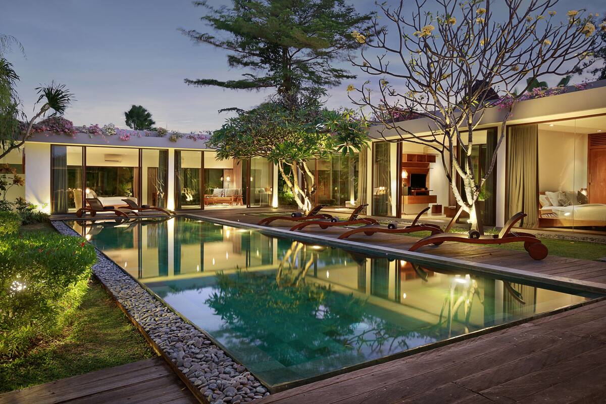 A modern house with a swimming pool, large glass windows, and a well-maintained garden.