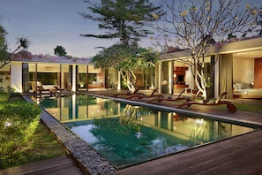A modern house with a swimming pool, large glass windows, and a well-maintained garden.