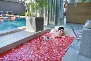 A woman relaxing in a bathtub filled with rose petals.