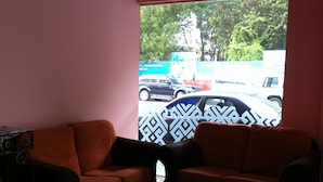 A room with two orange sofas, a patterned wall, and a view of parked cars outside. - D' Borneo Hotel (Kota Kinabalu)
