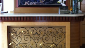 A reception desk with a framed picture of mountains, a clock, and a vase with white flowers. - D' Borneo Hotel (Kota Kinabalu)