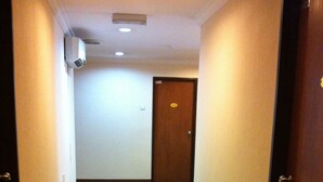 A narrow hallway with carpeted floors, white walls, and a wooden door at the end. - D' Borneo Hotel (Kota Kinabalu)