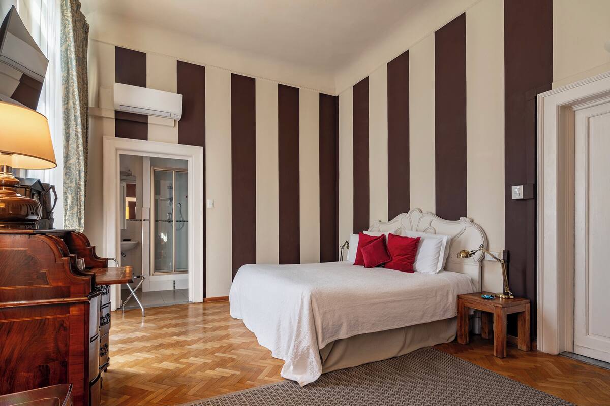 Un dormitorio con cama, mesita de noche, lámpara y cómoda de madera.