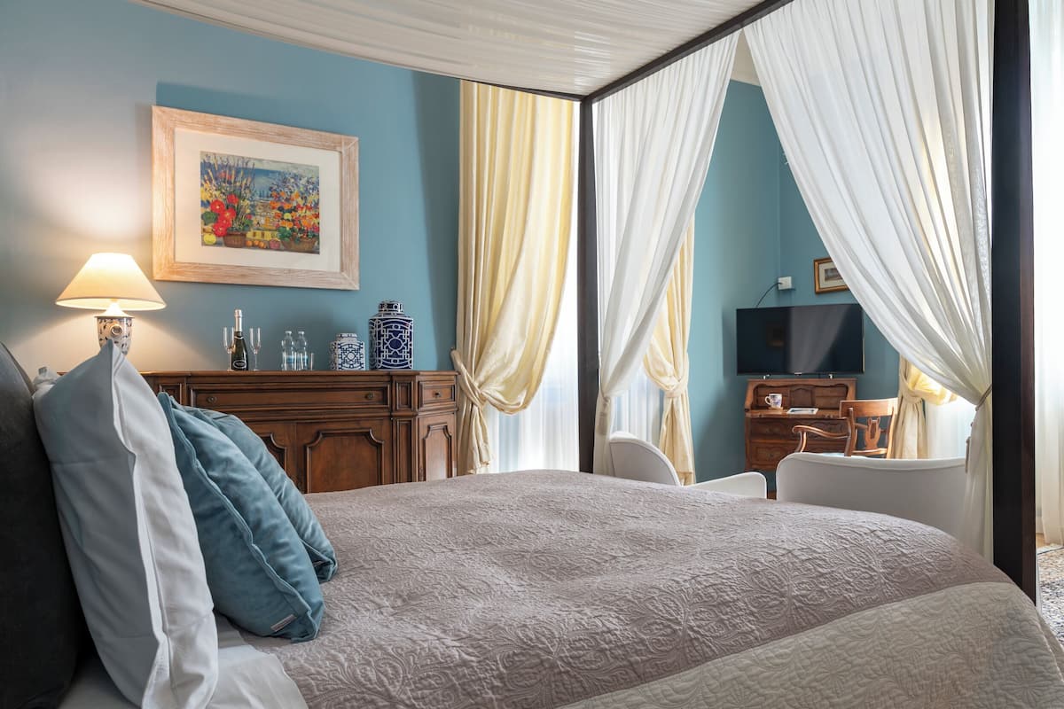 Un dormitorio con cama, escritorio, silla, televisor y cortinas.