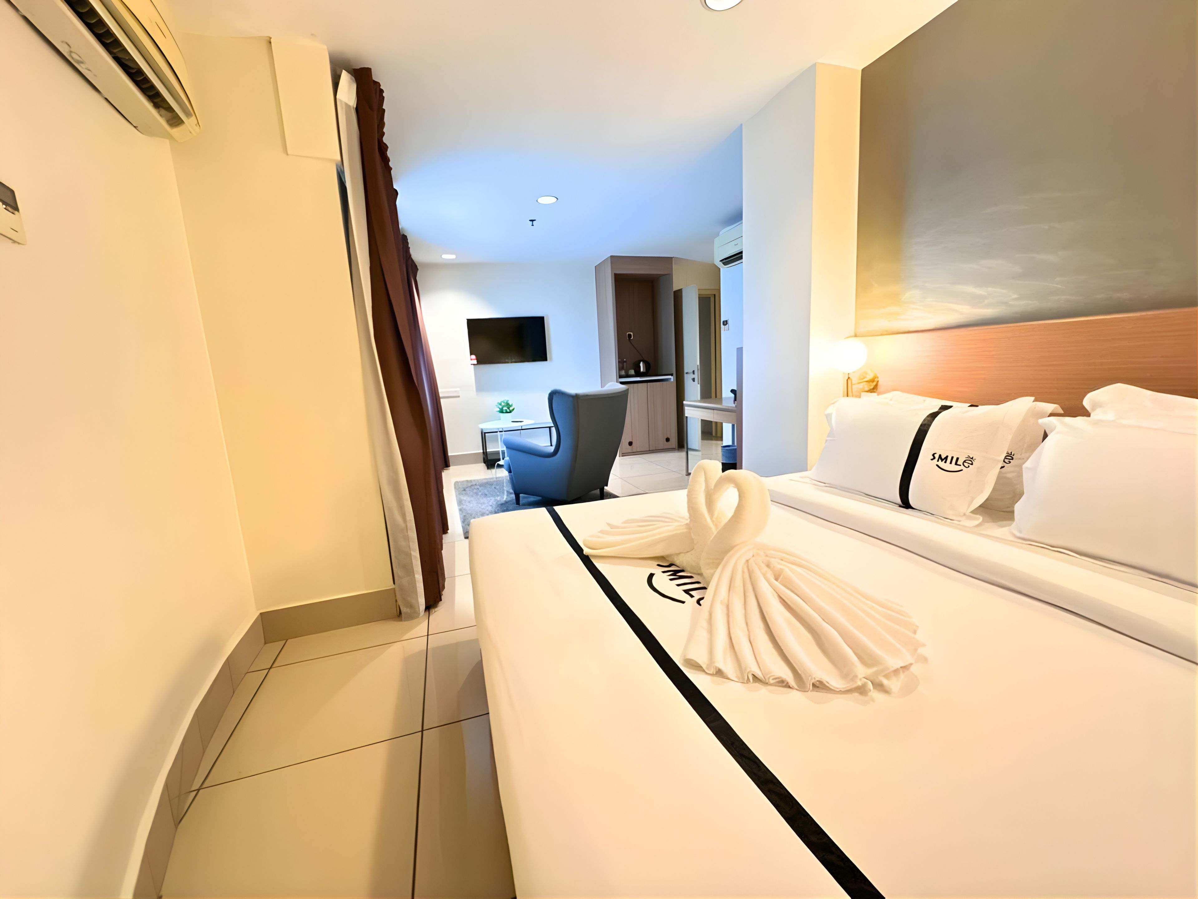 Una habitación de hotel con una cama bien hecha, un televisor en la pared y un escritorio con una silla.
