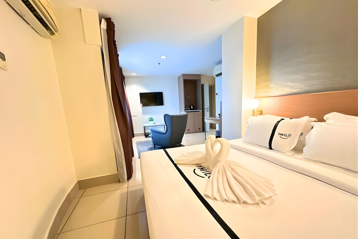 Una habitación de hotel con una cama bien hecha, un televisor en la pared y un escritorio con una silla.