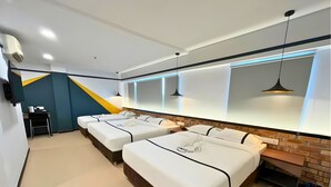 Ein Hotelzimmer mit drei Betten, einem Schreibtisch und einem Stuhl.
