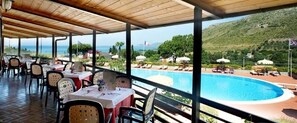A covered outdoor dining area with tables and chairs, overlooking a swimming pool and a mountainous landscape. - Residence Costa Di Kair Ed Din (Sperlonga)