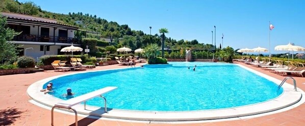 Een buitenzwembad, parasols bij het zwembad en ligstoelen
