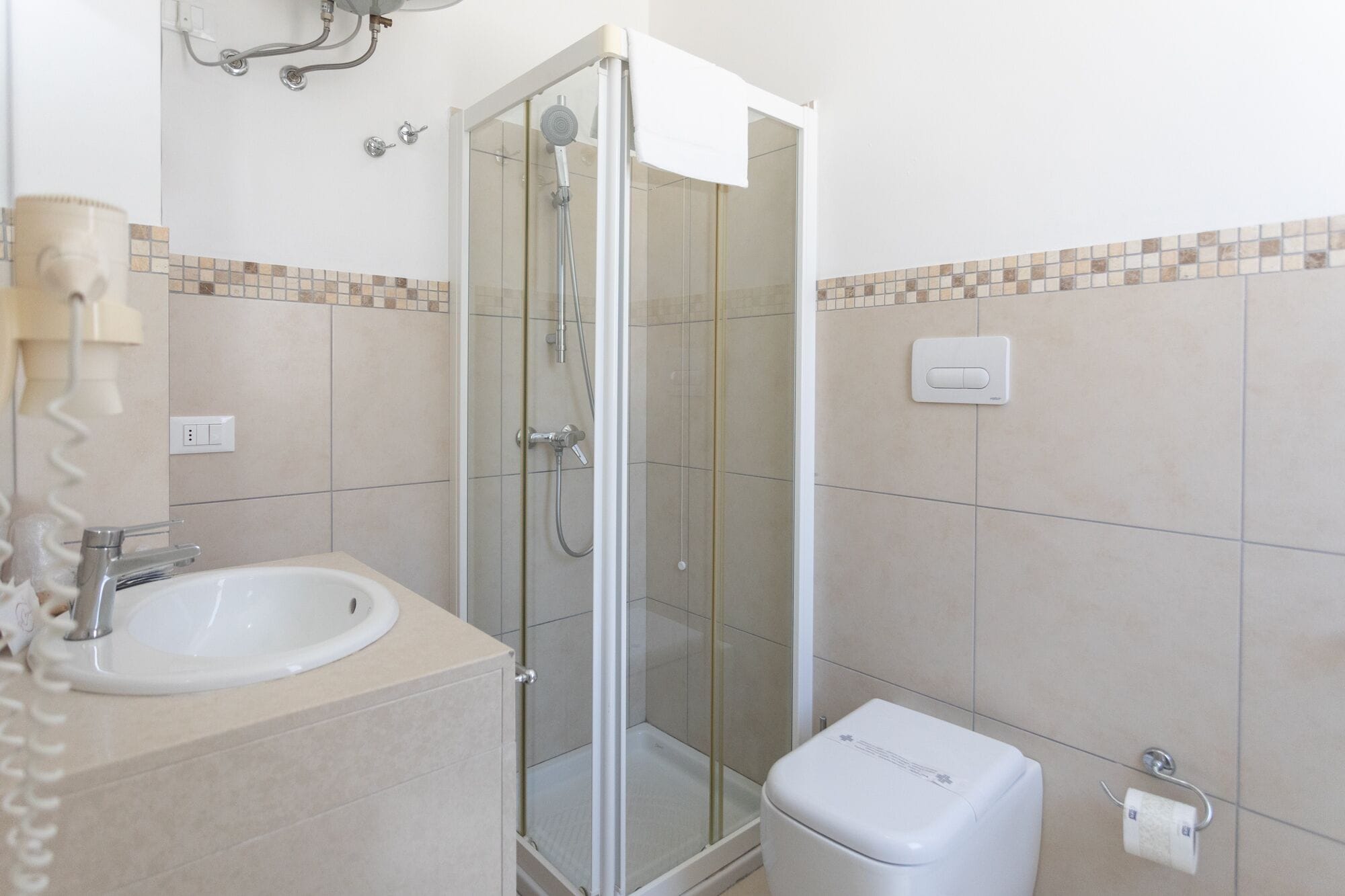 Un bagno con doccia vetro, lavandino e water.