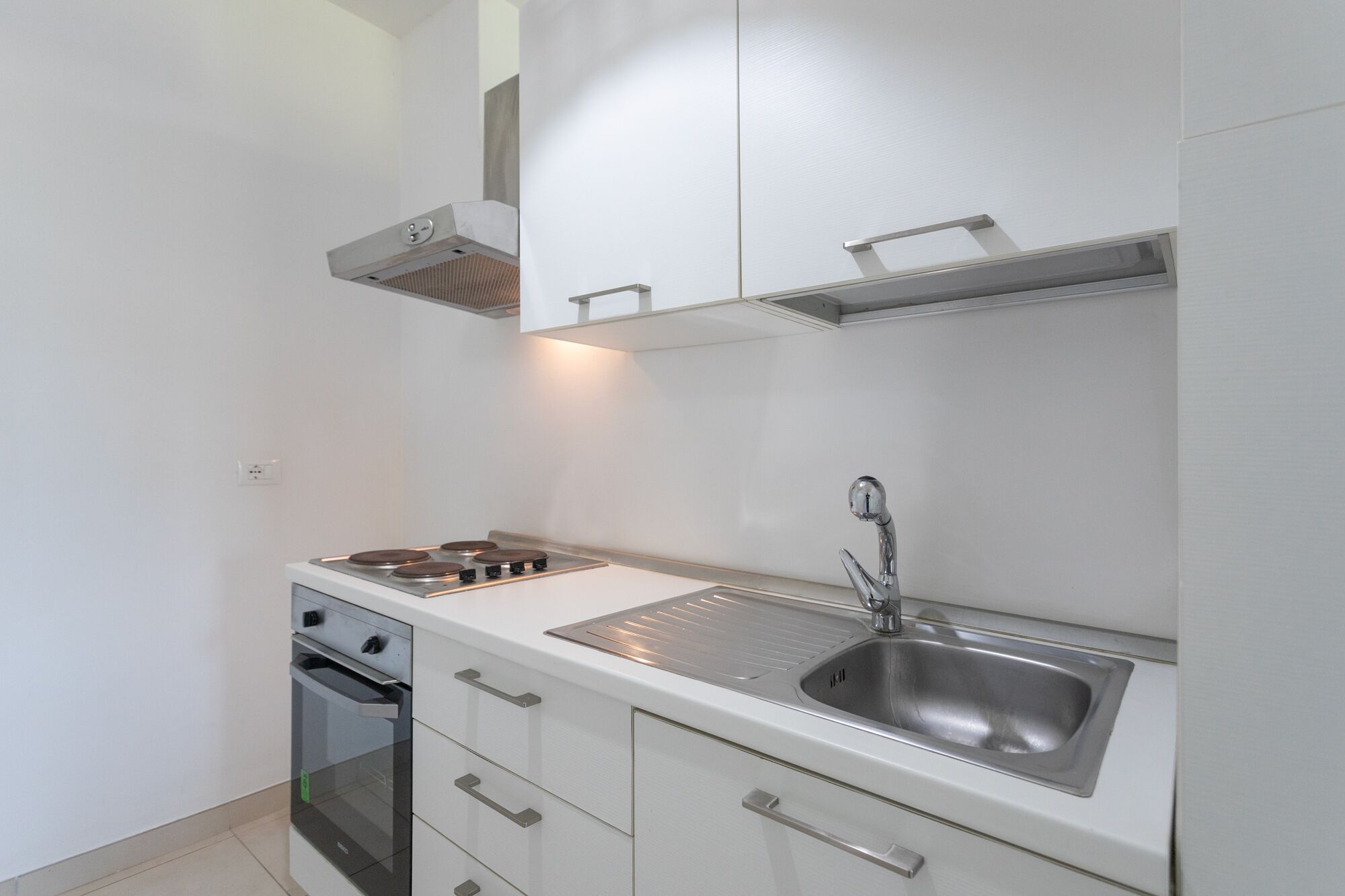 Une cuisine compacte équipée d’une cuisinière à gaz, d’un four et d’un évier en acier inoxydable.